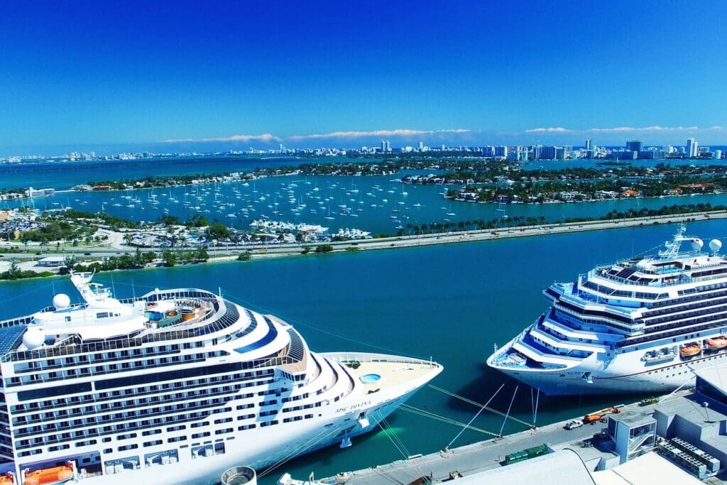 Cruise ships docked at port with a cityscape in the background, representing vacation options available through teacher cruise discounts.