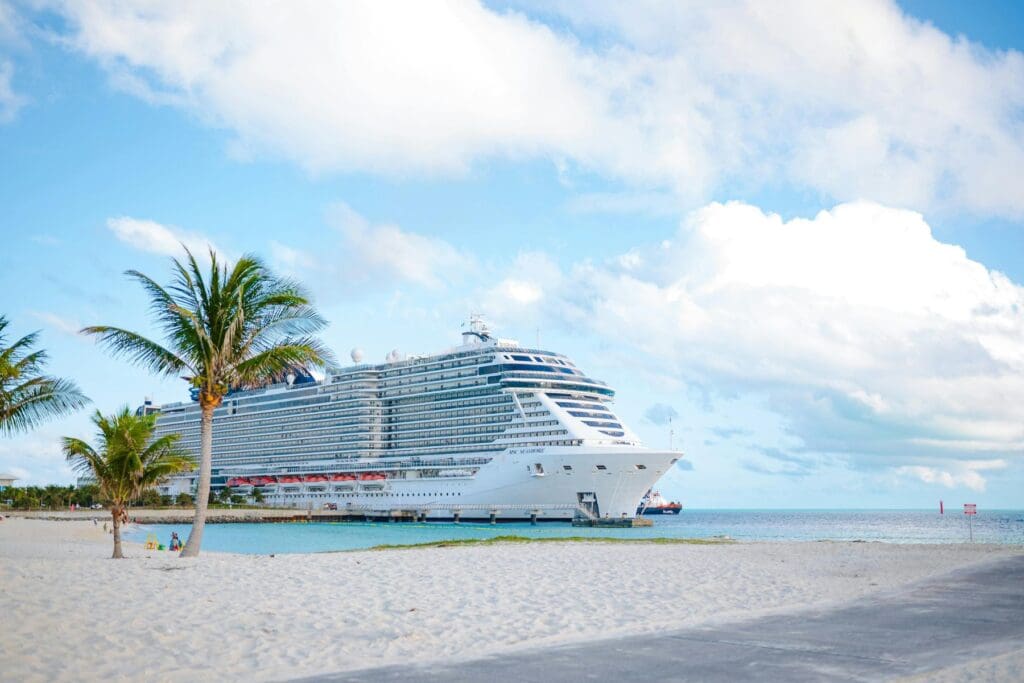 Cruise ship docked near a tropical beach, representing a relaxing cruise vacation option for teachers.