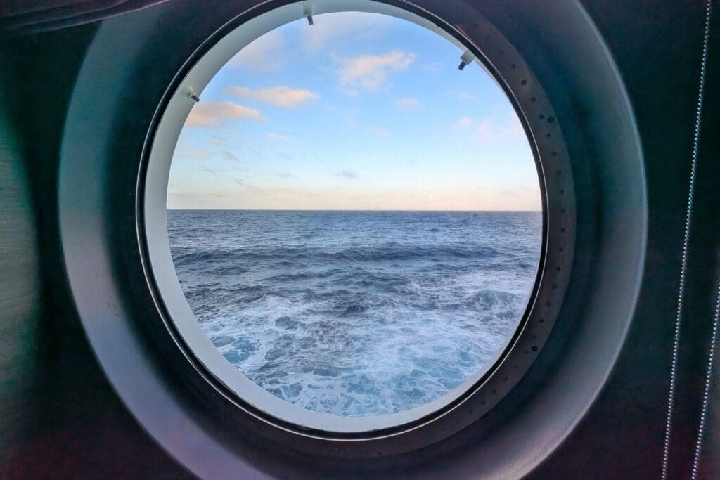 View of the open ocean through a cruise ship porthole, symbolizing a peaceful cruise getaway for teachers.
